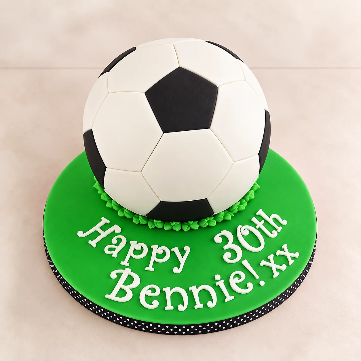 Black and white soccer ball birthday cake on a green board